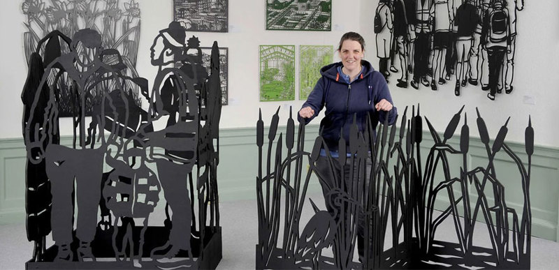 Martha Ellis stands alongside an assortment of cut-out sheet metal sculptures