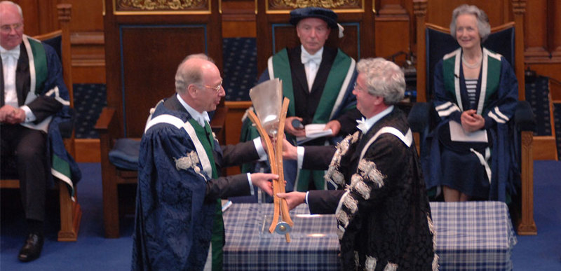 The University Mace being passed between two people at the QMU inauguration in 2007