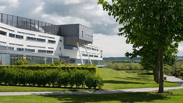 A view of Queen Margaret University Campus from outside with foliage in the foreground