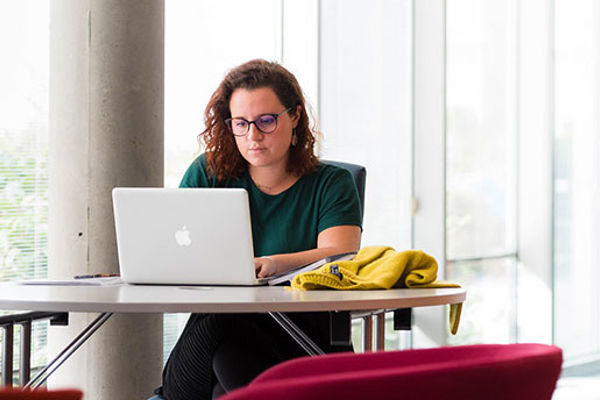 A young woman working intently on a Macbook laptop, QMU, Edinburgh