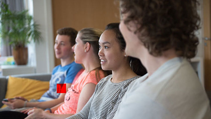 A row of Queen Margaret University students smiling and looking ahead