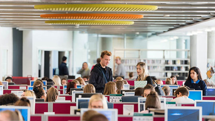 Group of QMU students smiling and talking together in a busy classroom, Edinburgh