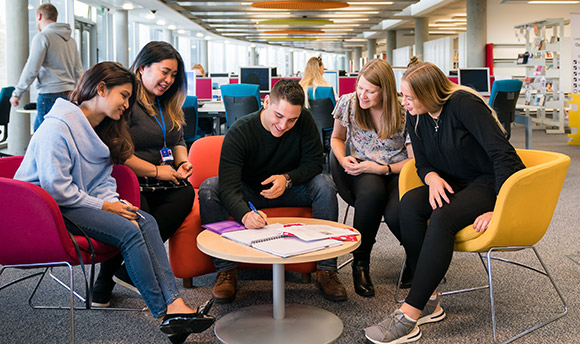 Group of strategic communication and PR students sitting round a small table and making notes