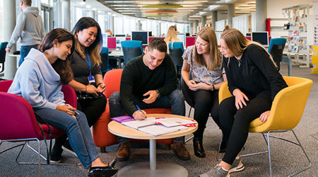 Group of strategic communication and PR students sitting round a small table and making notes
