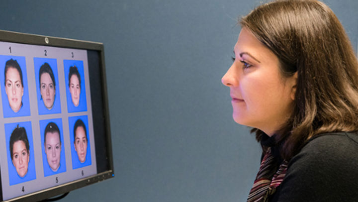 Queen Margaret University Psychology Student looking at a computer screen displaying 6 different faces numbered 1-6