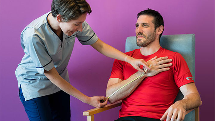 A Queen Margaret University student nurse examining the arm of a male patient
