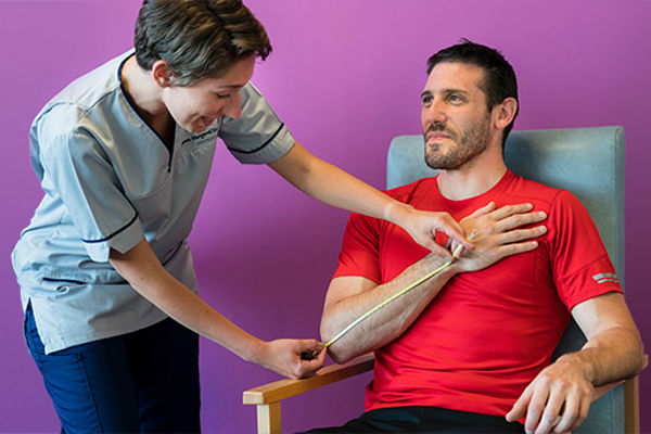 A Queen Margaret University student nurse examining the arm of a male patient