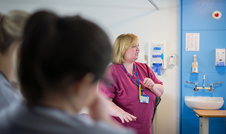A nurse talking as students watch and listen