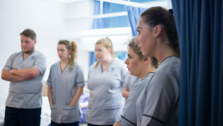 A row of QMU student nurses listening intently as a senior nurse speaks to them