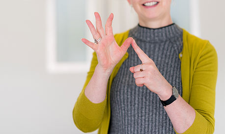 A woman in a yellow cardigan signing