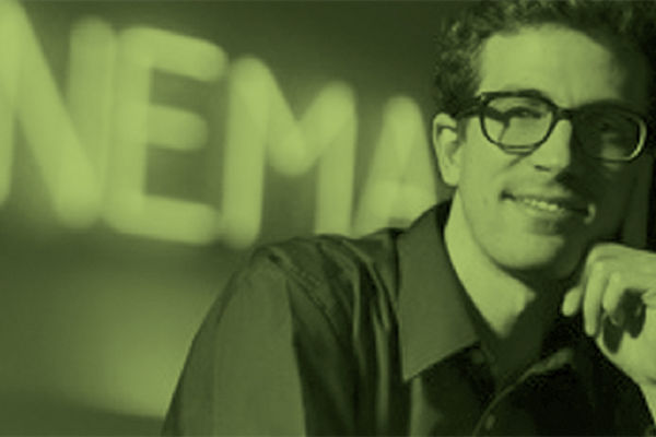 QMU media student smiling in front of neon sign