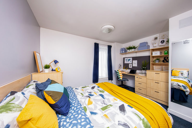 Inside a premium room, including a double bed, desk, mirror and chair