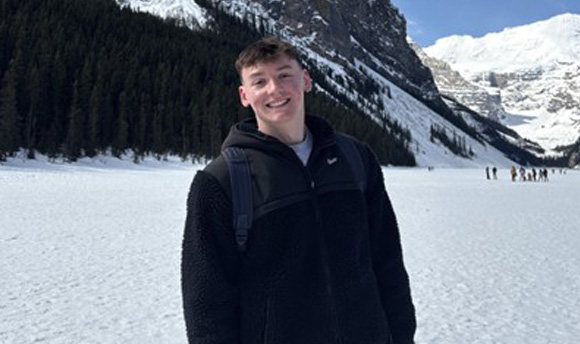 A person standing in front of a snowy mountain backdrop