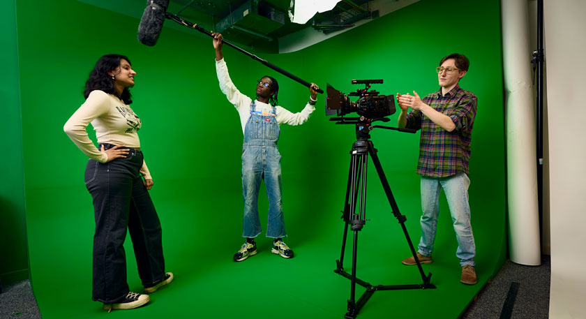 Students with filming equipment and a green screen