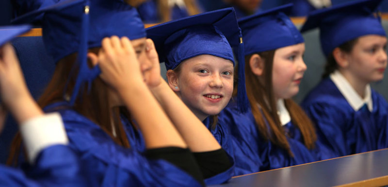 A group of young children wearing royal blue caps and gowns a the Children's University graduation ceremony.