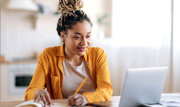A young woman works on a laptop at home