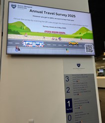 The Travel Survey 2024-25 poster shown on the screen at QMU reception