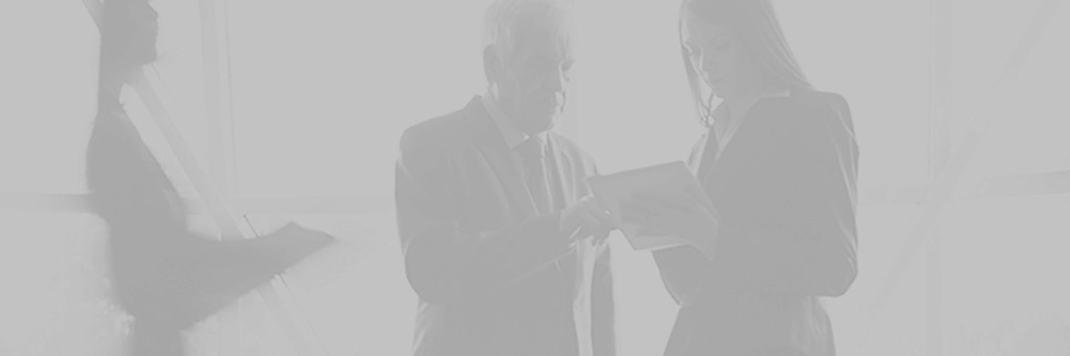 Greyscale photo of two professionals looking at paperwork as blurry people walk around them