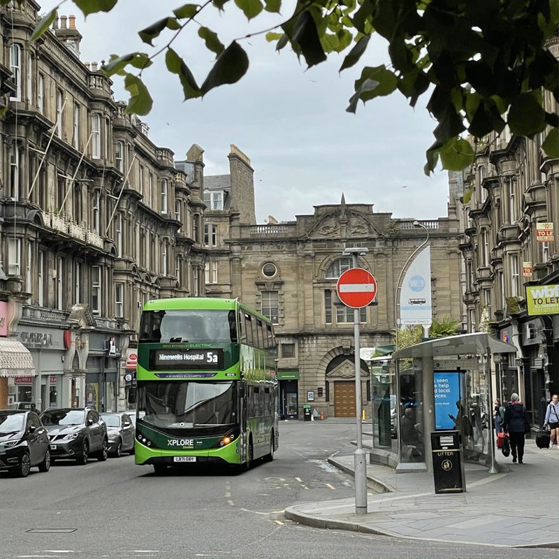 A green bus travels through Dundee city centre