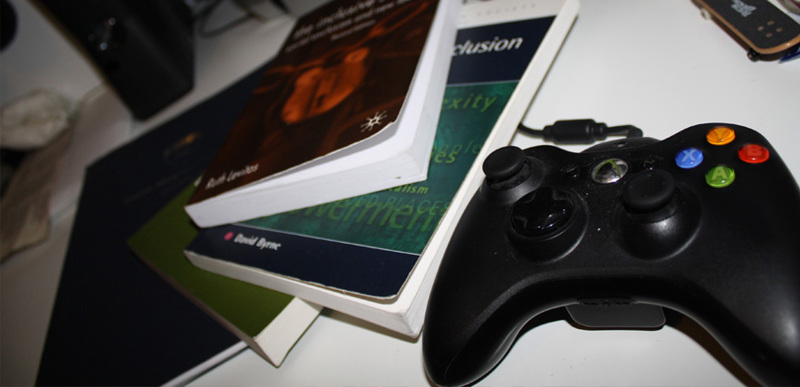 A stack of textbooks alongside an Xbox controller