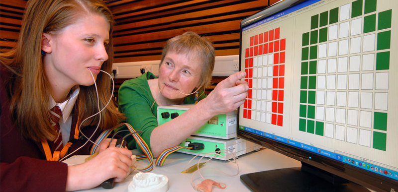 A student & Lecturer with probes in their mouths looking at a screen covered in coloured squares