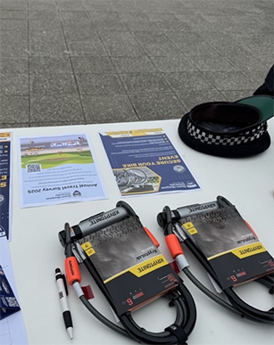 The Travel Survey 2024-25 poster displayed on a table during the Secure Your Bike Stand event.