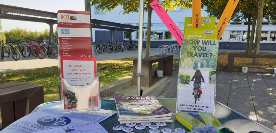 A stall set up on the campus forecourt, the stand is filled with cycling and travel pamphlets and paraphernalia.