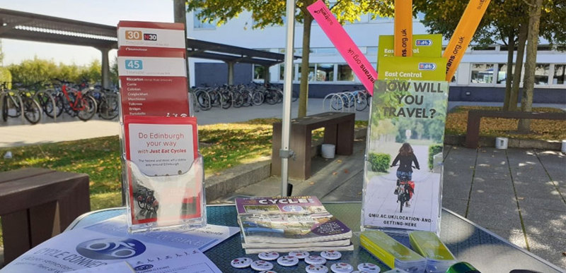 A stall set up on the campus forecourt, the stand is filled with cycling and travel pamphlets and paraphernalia.
