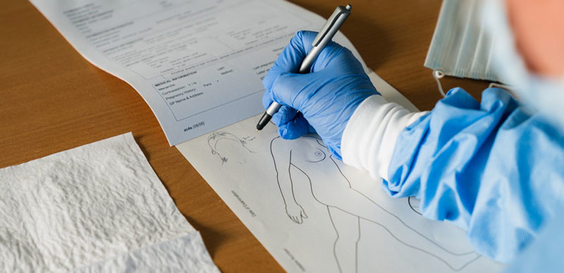 A person wearing scrubs demonstrates filling out a medical form.