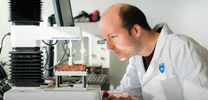 A scientist testing the texture of food on a piece of lab equipment