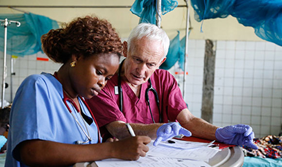 Two nurses sitting together in scrubs checking some paperwork