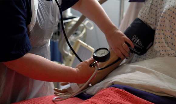 One of our nursing lecturers demonstrates applying a blood pressure cuff to the arm of a nursing mannequin.
