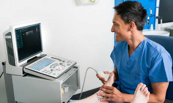 A technician using an ultrasound device on a patient's foot.
