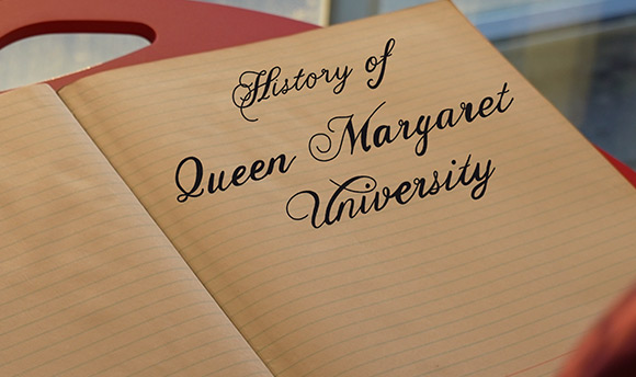 A close up of a lined notebook with text digitally added that reads "History of Queen Margaret University"