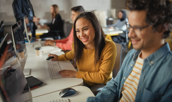 Several students working alongside one another in a library setting.