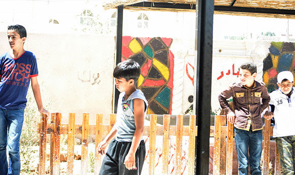 Four children standing idly outside in the sun