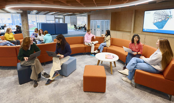 Several students sitting on the curved sofas within the library.