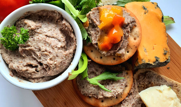 Parched pea pate on crackers with cheese, tomatoes and green leaves