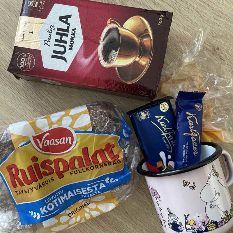 An assortment of Finnish treats, including chocolate, coffee, bread, and a Moomin branded mug.