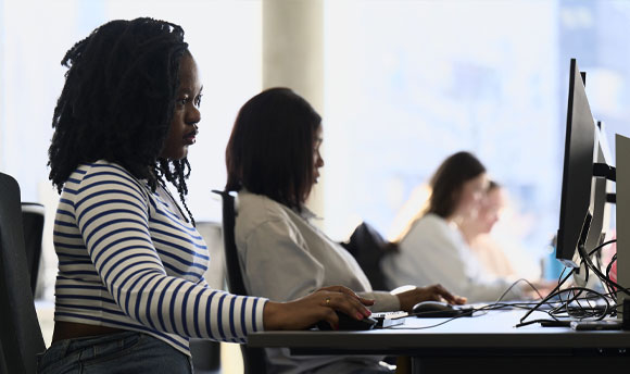 Two female students sit at computers in the library.