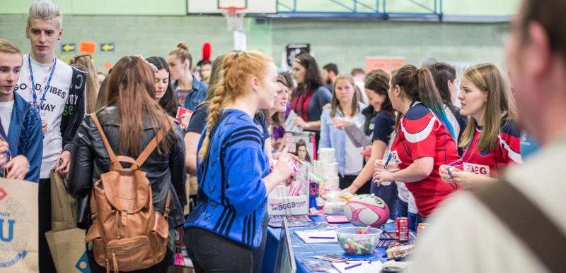 A crowd of people engaging in various parts of a lively induction fair