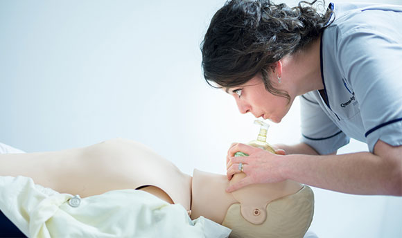 QMU student nurse practicing CPR on a Resusci Annie doll