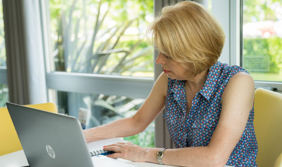 A female student takes notes beside her laptop