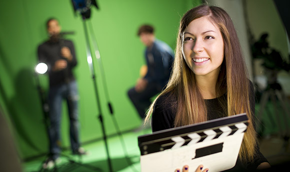 Female in front of a green screen with cameras