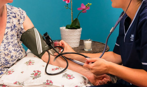 A woman having her blood pressure taken by a nurse