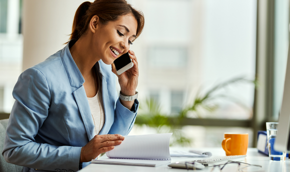 student on mobile call and reviewing notebook