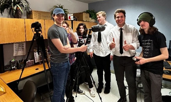 A group of students using various pieces of media toolkit, including cameras and microphones.