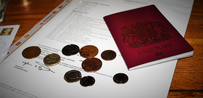 A British passport and some British coins on top of a letter addressed from QMU